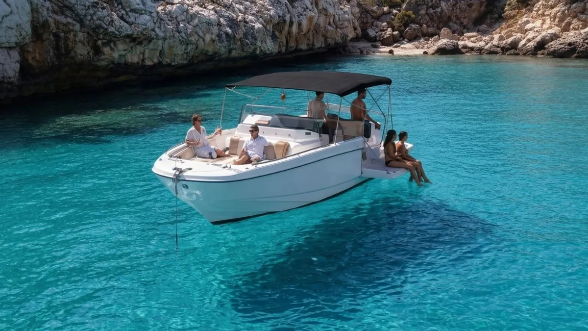 La barca de Holiboats fondeada en una cala turquesa con invitados a bordo