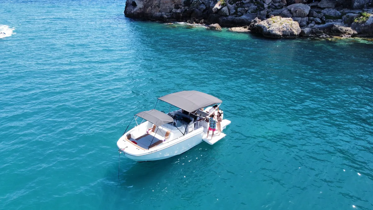 Vista aérea de la barca fondeada en una cala de aguas cristalinas