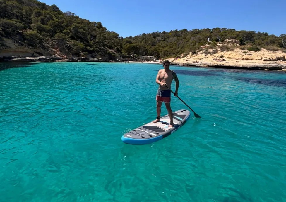 Invitado haciendo paddle surf en una cala turquesa de Mallorca