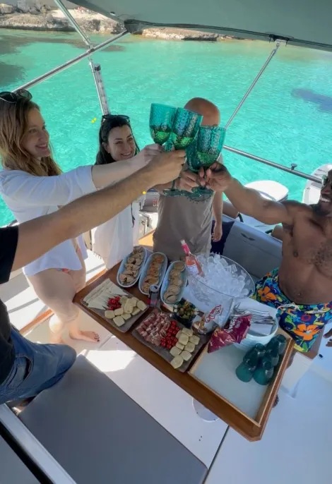Brindis entre amigos a bordo con un picnic frente al mar